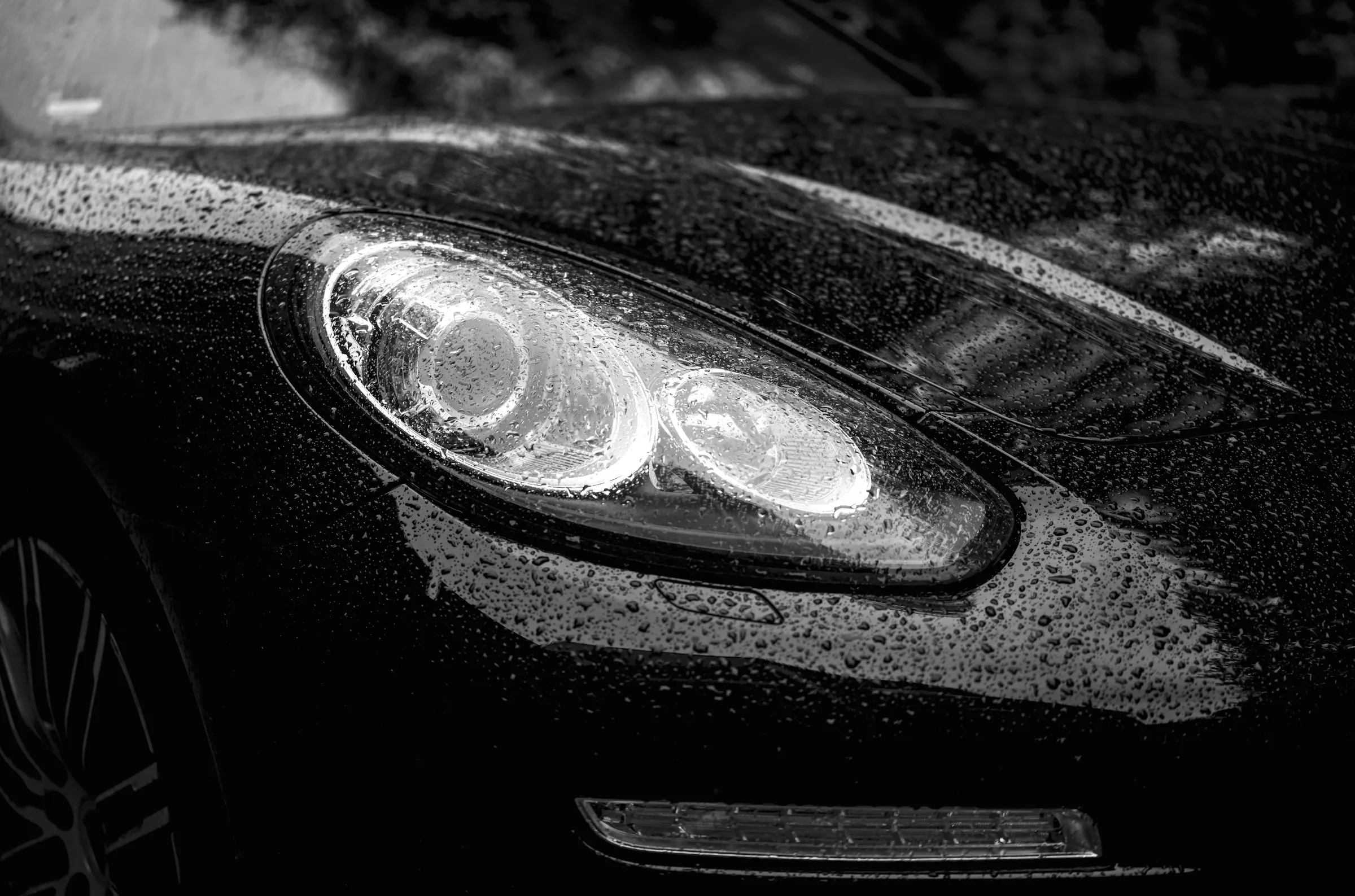 Close do farol e do capô de um carro preto com pintura espelhada