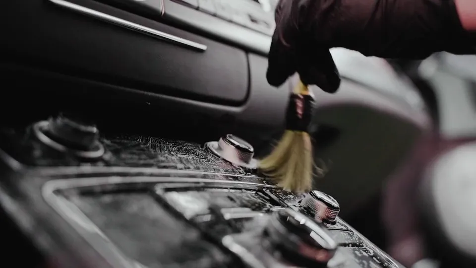 Pincel com espuma limpando os comandos do painel de um carro