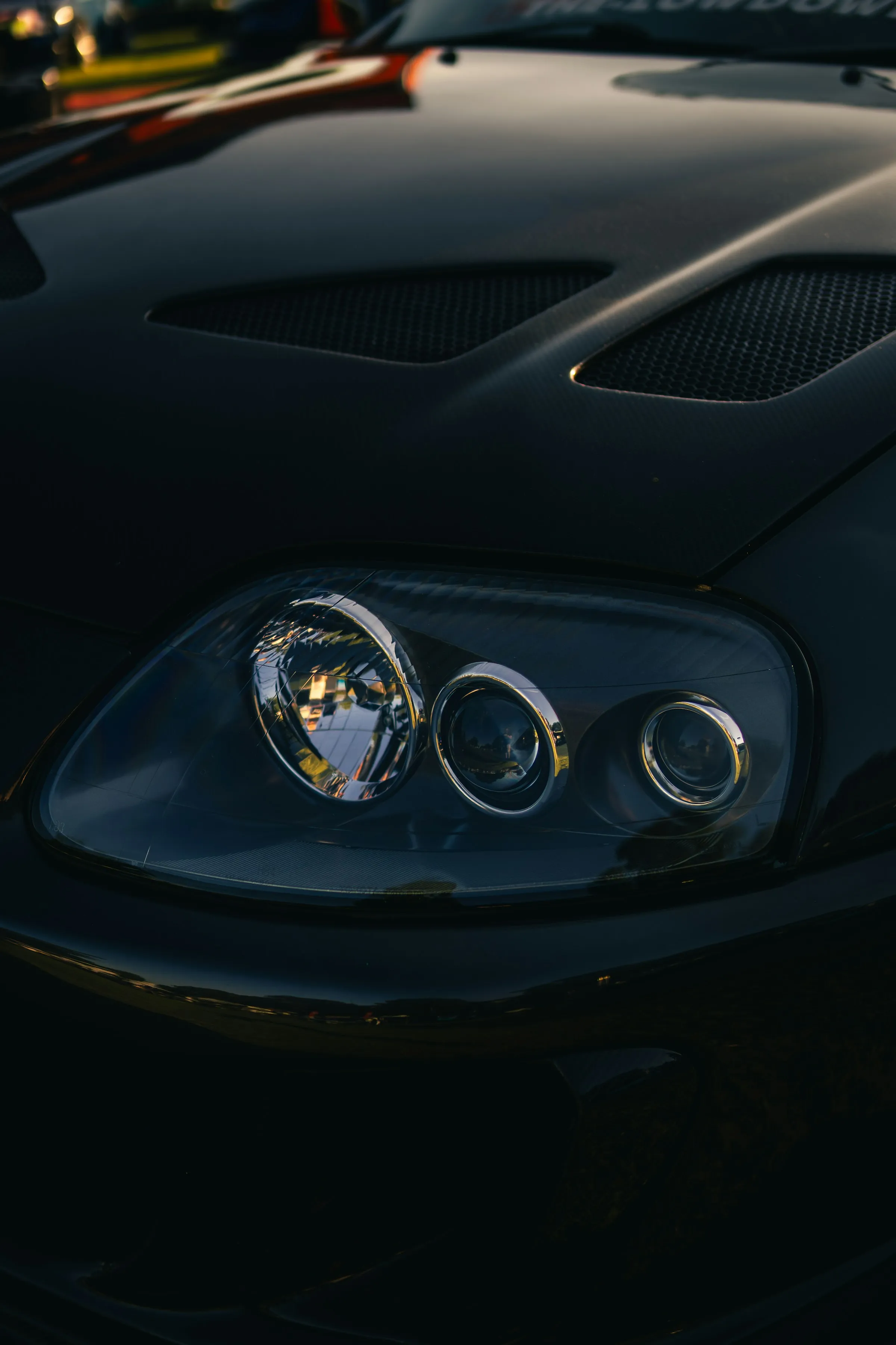 Farol de carro escuro em close, com lentes limpas e transparentes